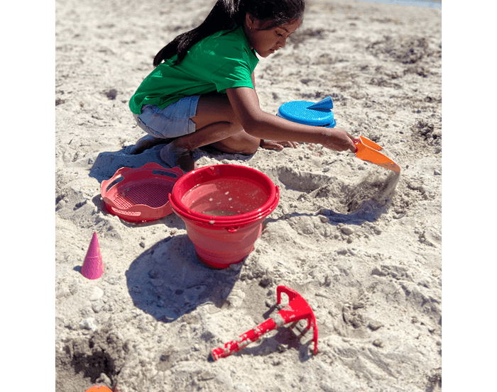 Child at beach playing with compacToys 7-in-1 Sand Toy Set. Available at www.tenlittle.com