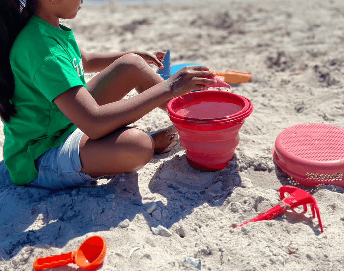 Child at beach playing with compacToys 7-in-1 Sand Toy Set. Available at www.tenlittle.com