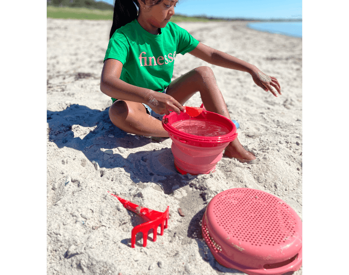 Child at beach playing with compacToys 7-in-1 Sand Toy Set. Available at www.tenlittle.com