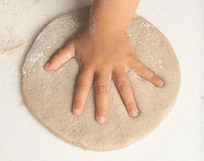 Child making hand print in sand casting medium for Eco-kids A Day at the Beach Kit