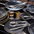 table de fête avec assiettes et plats noirs et bordure or