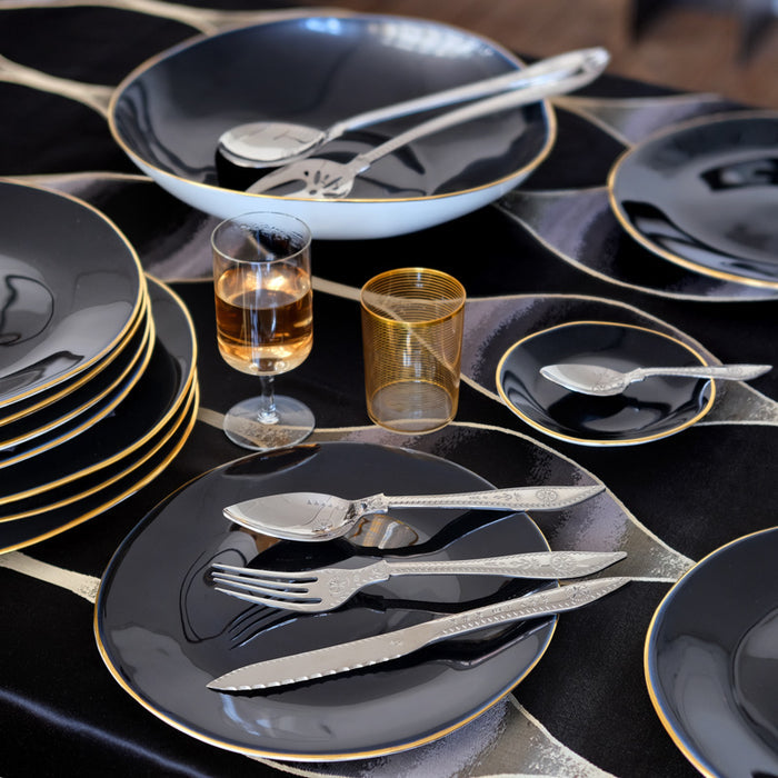 table de fête avec assiettes et plats noirs et bordure or