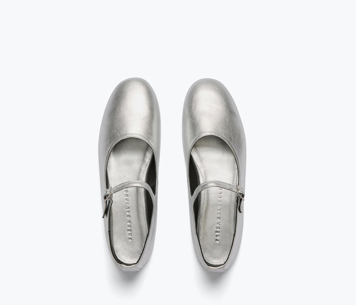Silver Aubrey Mary Jane flat by Freda Salvador with a rounded toe and ankle strap, shown on a calf-high model.