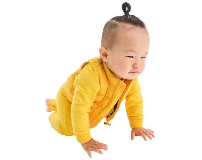 Baby crawling wearing Primary Baby Lightweight Puffer Vest - Mustard. Available at www.tenlittle.com