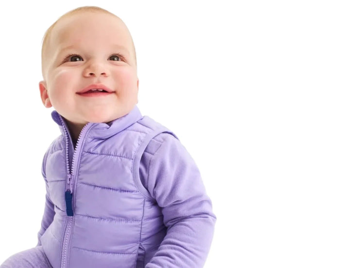 Baby sitting wearing Primary Baby Lightweight Puffer Vest - Iris. Available at www.tenlittle.com