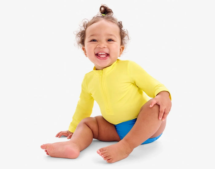 Baby sitting wearing Primary Swim Diaper - Blueberry. Available at www.tenlittle.com