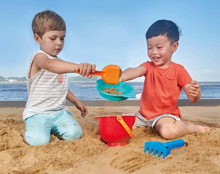 Boys playing with Hape Beach Toy Essential Set on the beach