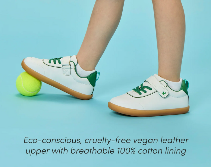 Side view child wearing Ten Little Centre Court Sneakers made with eco-conscious, cruelty-free vegan leather upper with breathable 100% cotton lining. Available at www.tenlittle.com