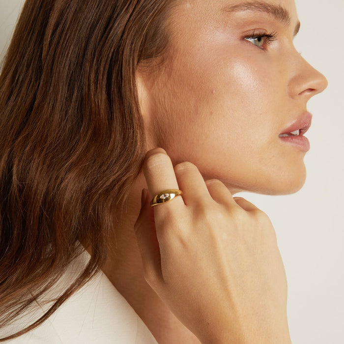 Model. Close-up of a woman wearing a gold earring on a plain background