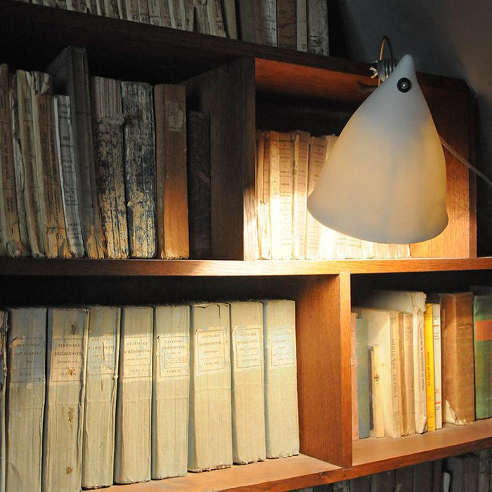 lampe à pince en porcelaine éclairant une bibliothèque - tsé tsé