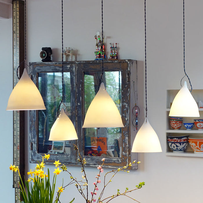 Salon avec beaucoup de lampes suspendues. Lampes en porcelaine translucides en forme de cornet. Tsé tsé