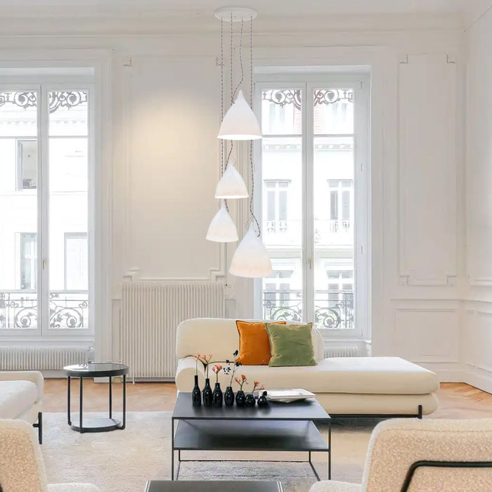 Salon de type hausmanien avec décoration moderne. Méridienne beige, table basse noire avec des soliflores tsé tsé noirs et un plafonnier lampes cornettes en porcelaine.