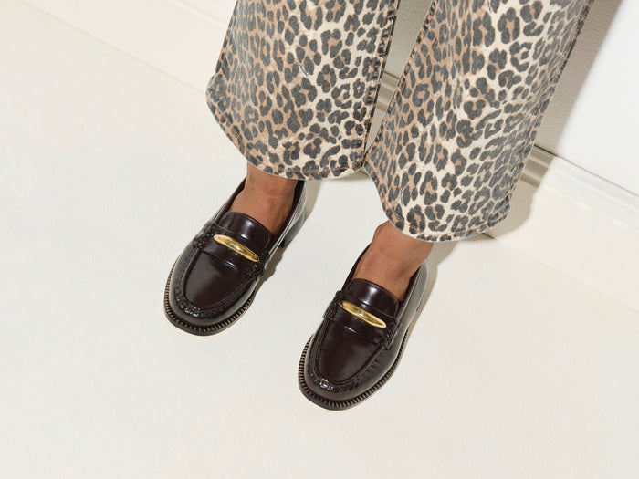 Freda Salvador Elba penny loafer with crescent charm in black leather, showcasing classic slip-on design and decorative metallic detail