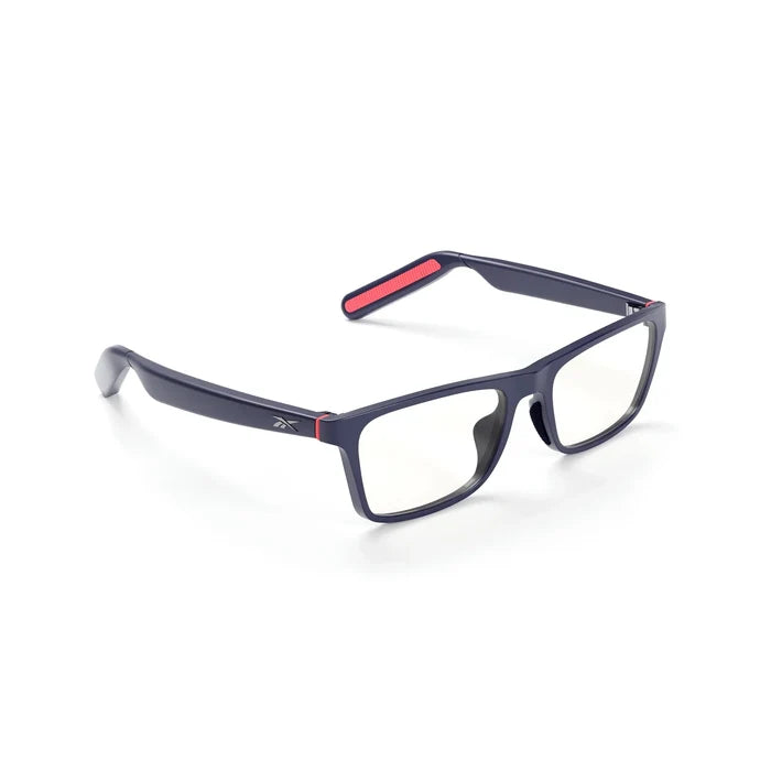 Reebok Dash rectangular smart glasses with a dark blue frame, clear lenses, and red accents on the temples and ends. Features open-ear audio for privacy. Shown on a white background.