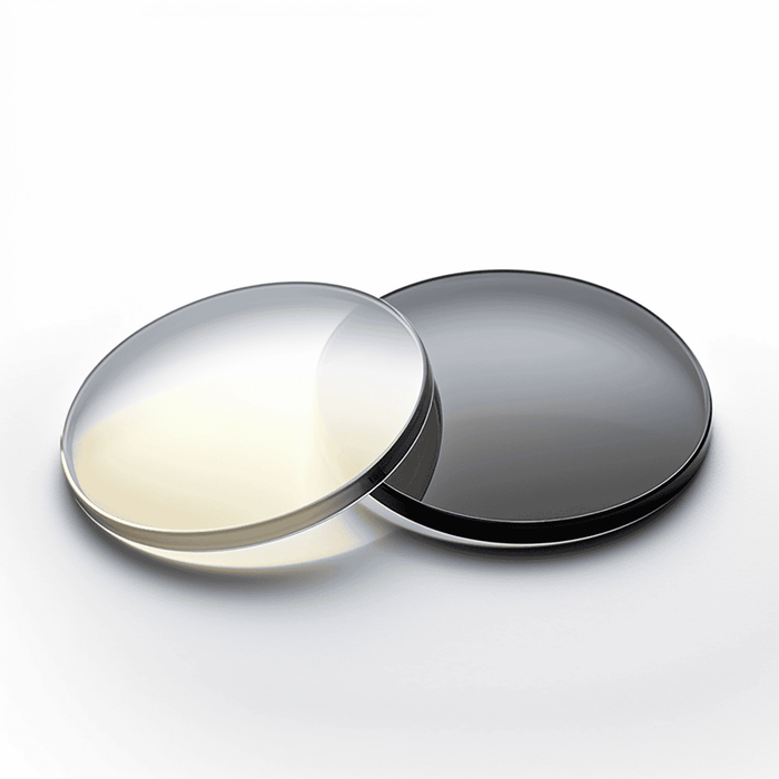 Two Lucyd Extra Lenses rest side by side on a white surface—one clear, one dark—to show the contrast between standard prescription lenses and photochromic options.