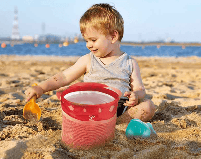 Child at beach playing with Hape Fold and Go Beach Set. Available at www.tenlittle.com