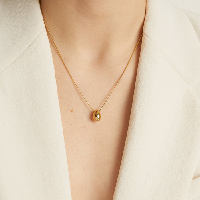 Model Gold necklace with a pendant on a person wearing a white outfit