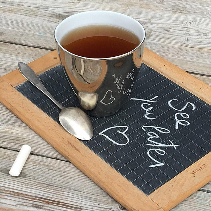 grande tasse à thé extérieur platine effet miroir posée sur une ardoise d'écolier - tsé tsé