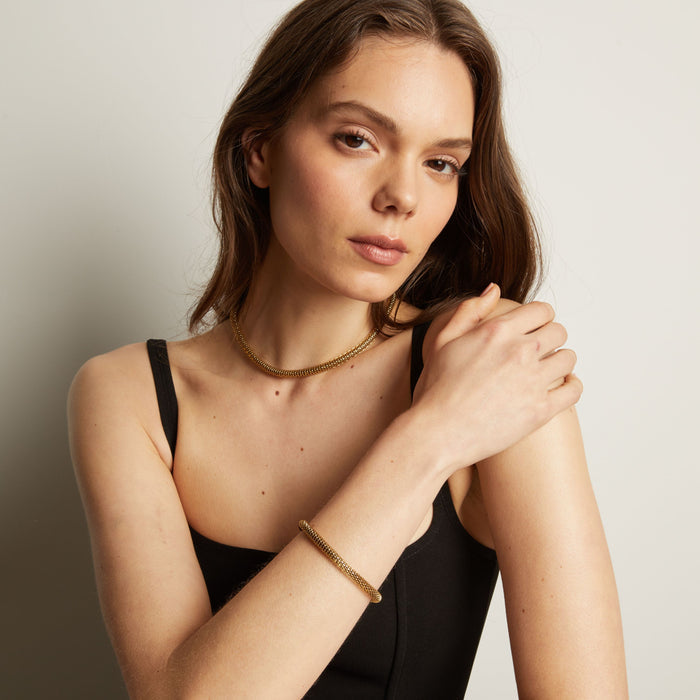 Gold chain bracelet and necklace on woman in black tank top. Model