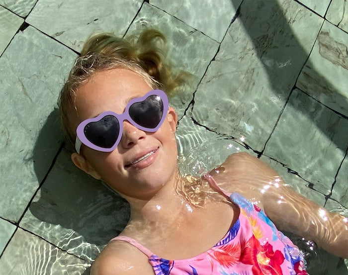 Girl in pool wearing Ten Little Roshambo Heart Sunglasses - Lilac. Available at www.tenlittle.com