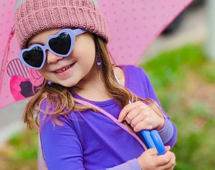 Girl holding umbrella wearing Ten Little Roshambo Heart Sunglasses - Lilac. Available at www.tenlittle.com