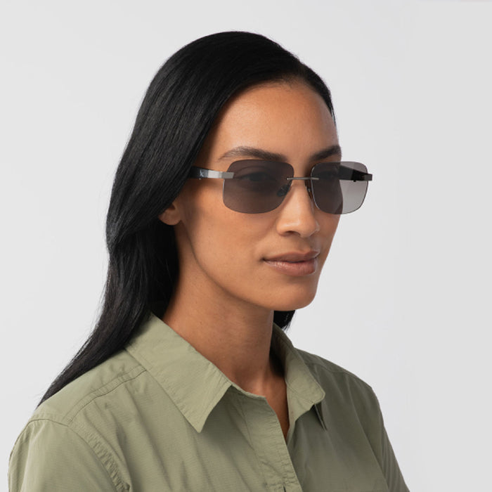 A woman with long black hair wears Eddie Bauer Horizon UV400 polarized sunglasses and a light green button-up shirt, gazing slightly to the side against a plain light background.