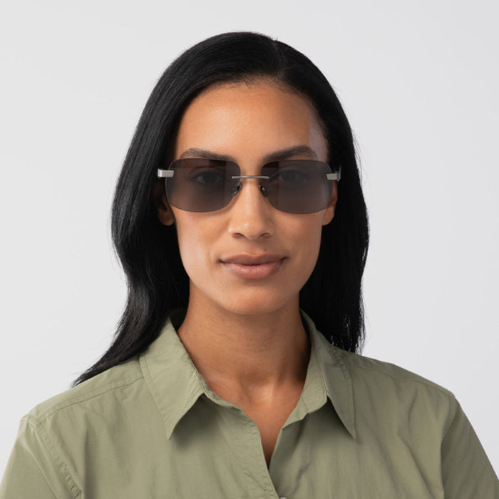 A woman with long black hair models the Eddie Bauer Horizon UV400 polarized sunglasses and an olive green collared shirt, standing against a plain light background and facing forward with a neutral expression.
