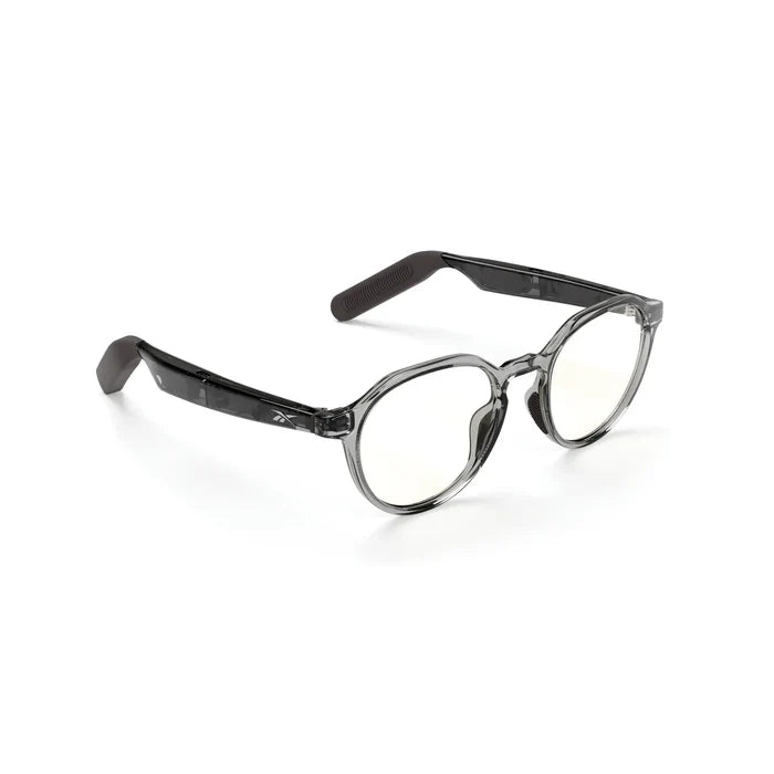 Reebok Jet round smart eyewear features black temple arms and slightly tinted lenses for a sleek look, with open-ear audio functionality. Displayed on a white background.