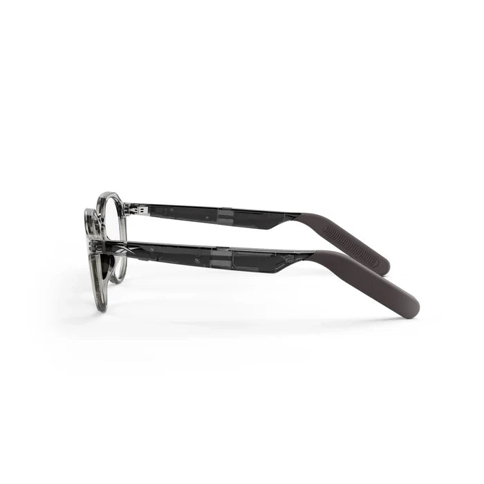Side view of Reebok Jet smart glasses with transparent gray frames and dark matte-finish temple arms featuring open-ear audio, set against a white background.