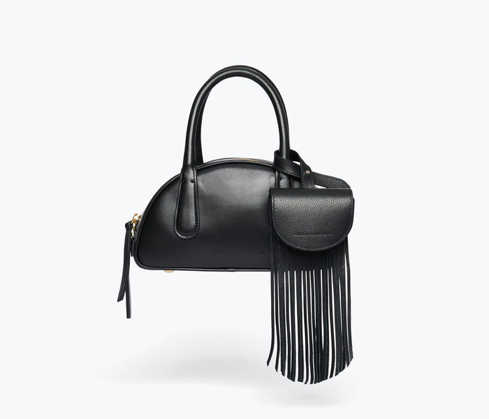 Black calf leather Joni fringe bag charm by Freda Salvador with tassel details hanging from a sleek bag.