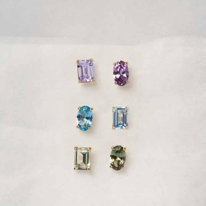 Model. Three sets of gemstone earrings on a light gray background