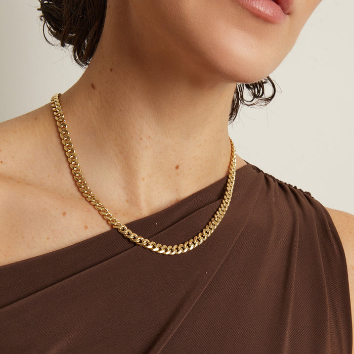 Model. Gold chain necklace worn by a person with a neutral background