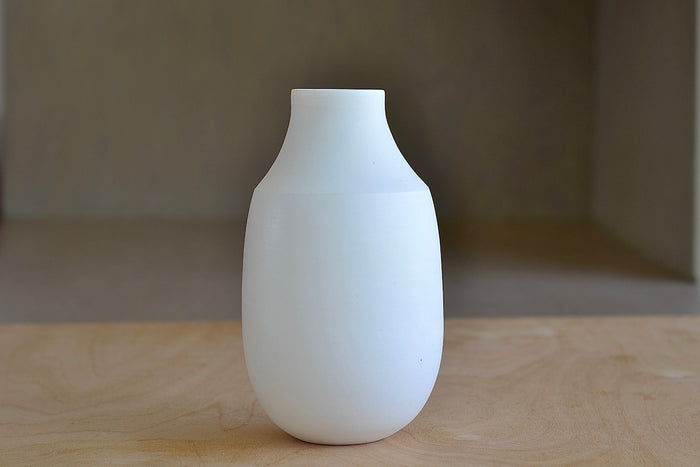 Lilith Rockett Vase with Neck "B" is Reminiscent of an eggshell, this vase is wheel thrown porcelain with gloss glaze on the interior and an unglazed exterior. It has been sanded smooth and it is very stable despite its rounded bottom.