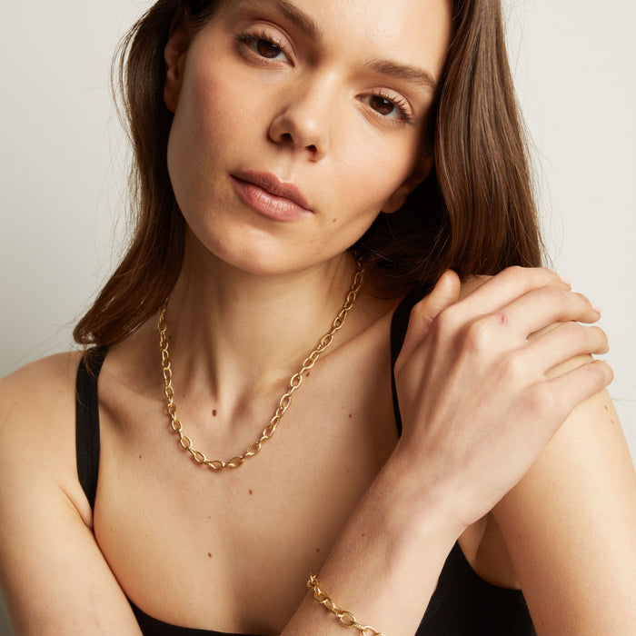 Model. Gold chain necklace on a person's neck with a neutral background.