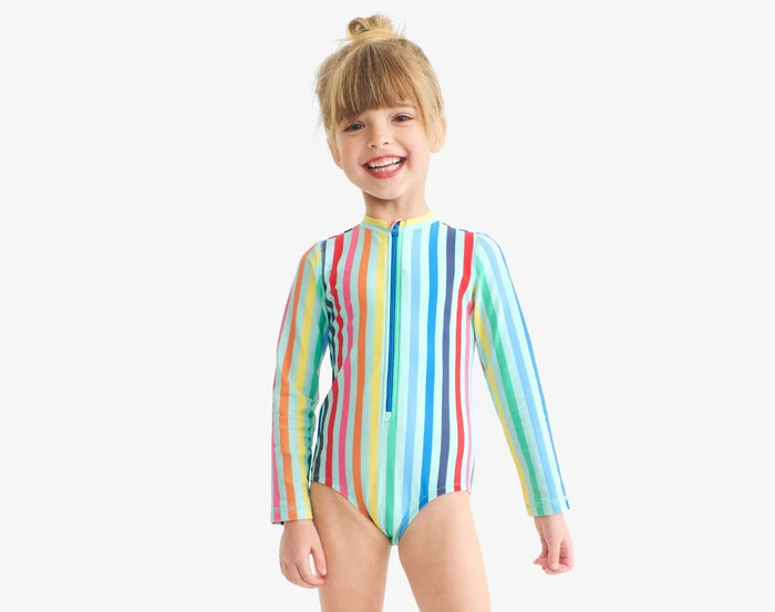 Child wearing Primary Long Sleeve One-Piece Rash Guard - Mist Rainbow Stripe. Available at www.tenlittle.com