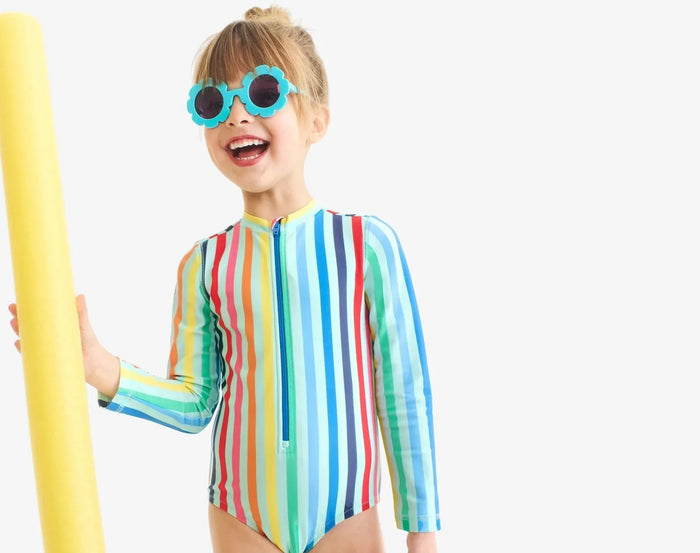Child wearing Primary Long Sleeve One-Piece Rash Guard - Mist Rainbow Stripe. Available at www.tenlittle.com