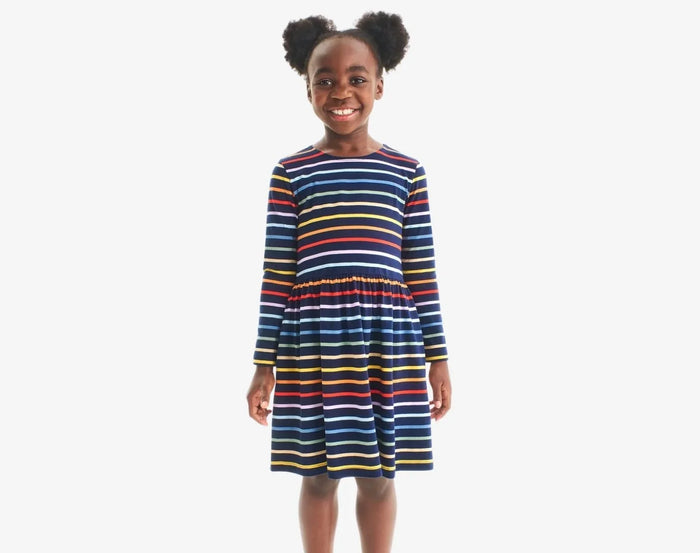 Child wearing Primary Long Sleeve Pocket Dress - Rainbow Stripe - Navy / Rainbow Stripe. Available at www.tenlittle.com