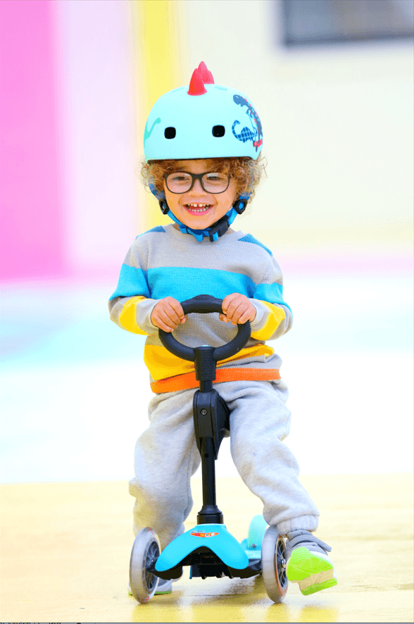 Child sitting on Micro Kickboard Mini 3in1 Deluxe Scooter. Available at www.tenlittle.com