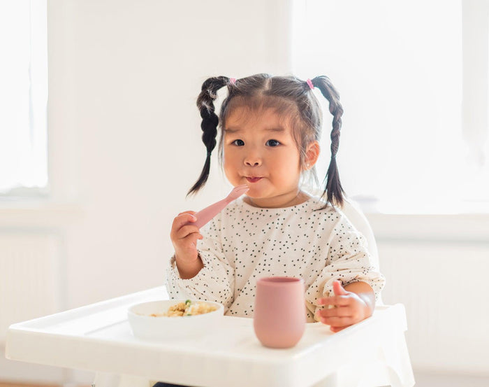 Baby Holding Ezpz Mini Utensils set of 2 in blush- Available at www.tenlittle.com
