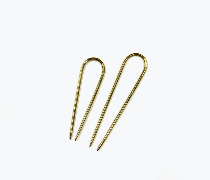 NATALIE BORTON brass French pin accessory with intricate design, shown on a neutral background.