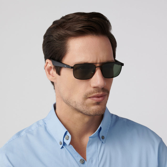 A man with short brown hair wears Eddie Bauer Navigator UV400 polarized sunglasses and a light blue button-up shirt, gazing slightly to the side against a plain light background.