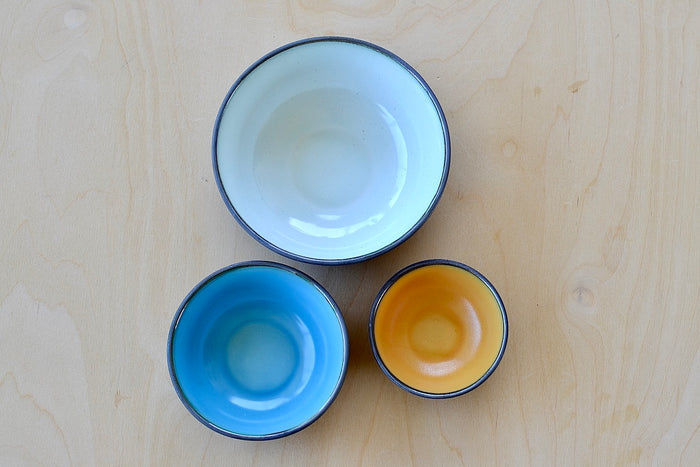 Set of three small stacking bowls by One Kiln in white, Blue and yellow.