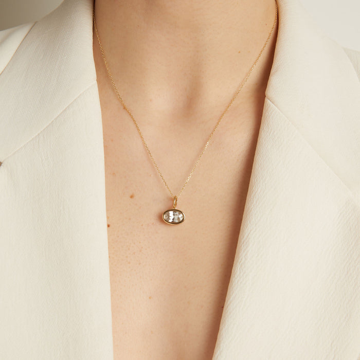Model Gold necklace with a pendant on a person wearing a white blazer.