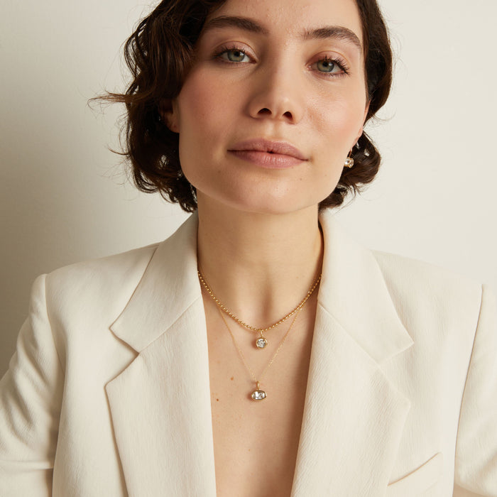 Model Woman wearing a white blazer and gold necklace against a neutral background