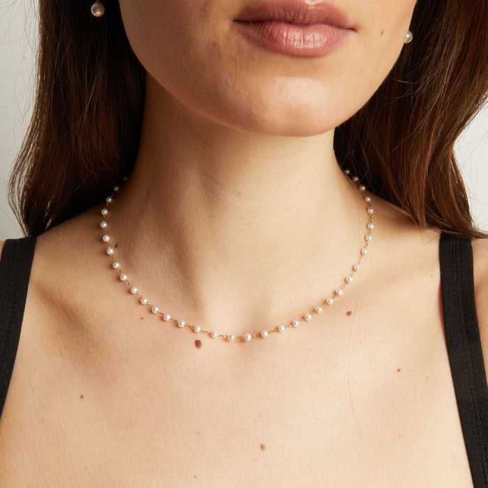 Model. Pearl necklace worn by a person with a neutral background.