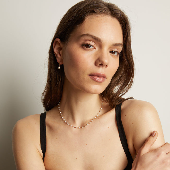 Model. Pearl necklace worn by a person with a neutral background.