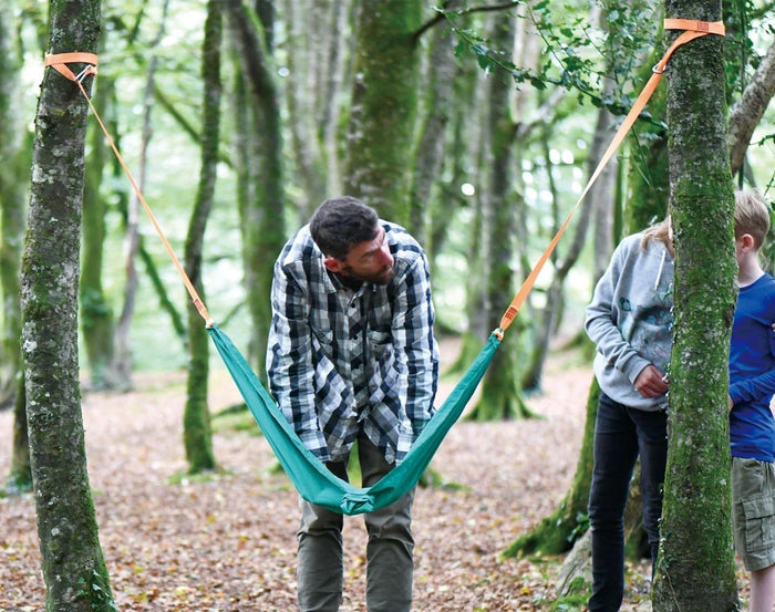 Dad setting up Hape Pocket Swing between two trees