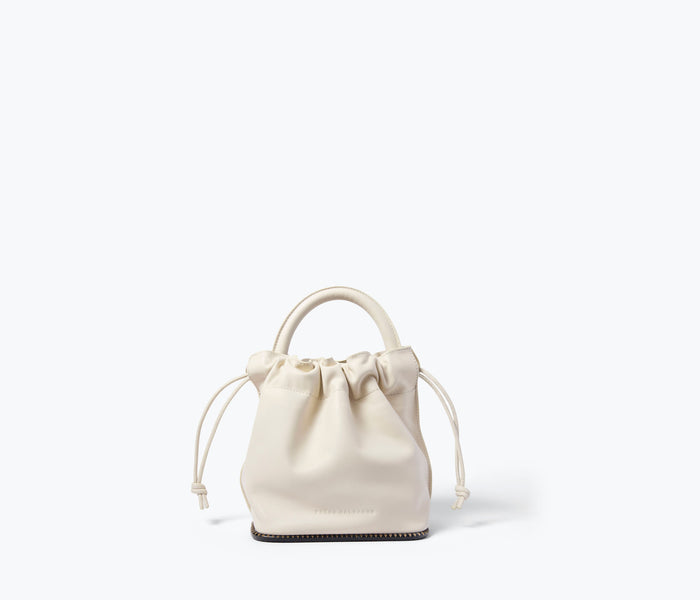 Freda Salvador Ruby bucket bag in bone calf leather, front view showcasing sleek design and compact size.