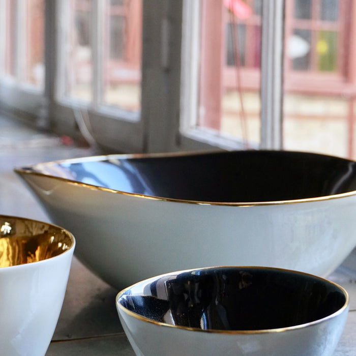 gros plan sur des saladiers en porcelaine avec interieur noir et bordure or