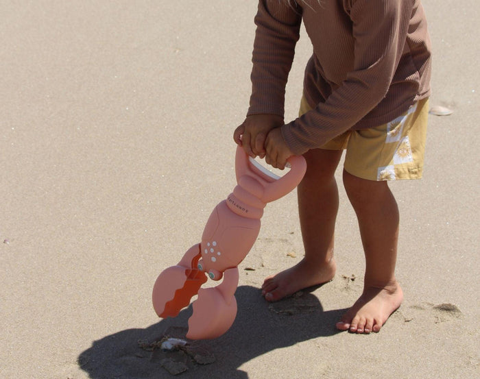 Child scooping sand with Sunnylife Sand Claw - Lobster. Available at www.tenlittle.com